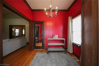 Living area with a wealth of natural light, wood-type flooring, a chandelier, and crown molding