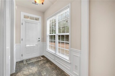 Entrance foyer featuring a decorative wall, wainscoting, stone finish flooring, and visible vents