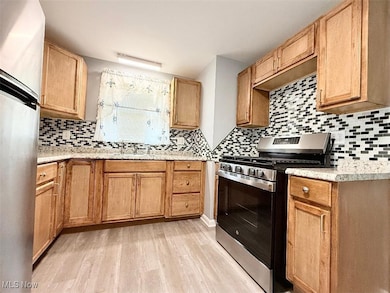 Kitchen with stainless steel appliances, backsplash, light laminate wood finished floors, and updated counter tops.