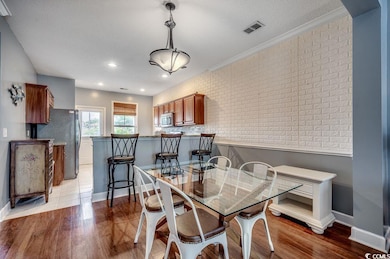 Dining area featuring light wood-style flooring, a textured ceiling, and crown molding