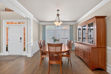 Dining area with wood finished floors, crown molding, and a wainscoted wall