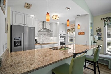 Kitchen with a sink, stainless steel appliances, wall chimney range hood, visible vents, and light stone countertops