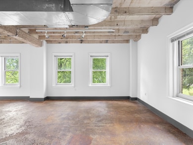 Unfurnished room featuring healthy amount of natural light and unfinished concrete flooring