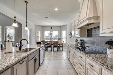 Kitchen features a decorative hood and backsplash,