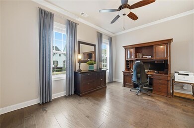 Office space with crown molding, light wood-style floors, and a ceiling fan