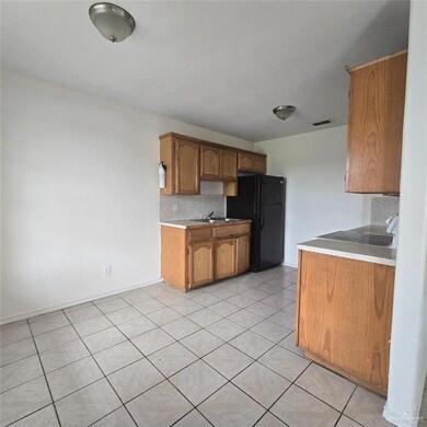 Kitchen featuring black refrigerator, sink, tasteful backsplash, and light tile patterned floors