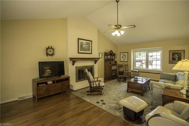 Living room features gas log fireplace, wood floors and vaulted ceiling.