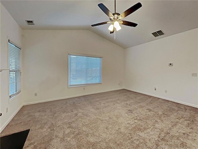 Unfurnished room featuring plenty of natural light, a ceiling fan, carpet, and lofted ceiling