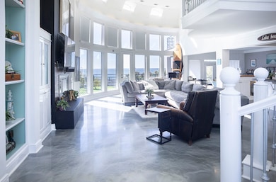Living area with a high ceiling, built in shelves, and concrete flooring