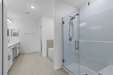 Bathroom with double vanity, a stall shower, light tile patterned flooring, and a garden tub