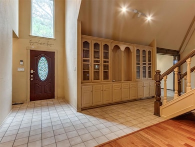 Foyer entrance with light tile patterned floors, stairway, and a towering ceiling