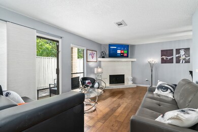 Open living space with wood burning fireplace and doors leading to a private patio.