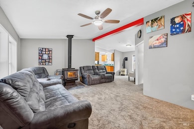 Living area with a wood stove, carpet flooring, and a ceiling fan