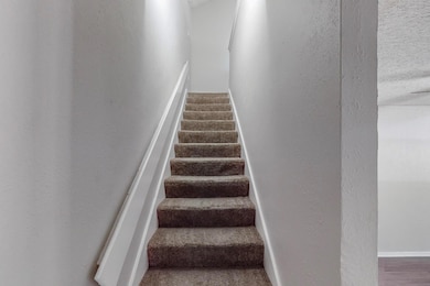 Staircase featuring a textured wall and baseboards