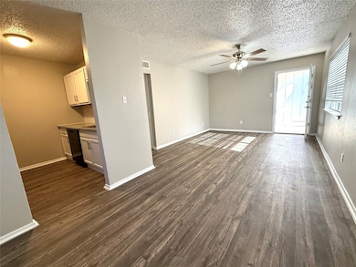 Unfurnished living room with dark wood-style floors, a ceiling fan, and a textured ceiling