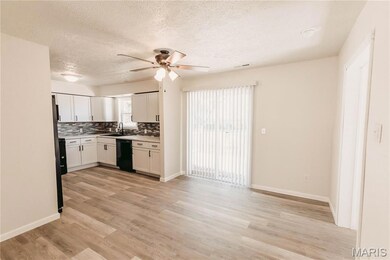 Kitchen featuring decorative backsplash, white cabinets, a textured ceiling, light countertops, and light wood-style flooring