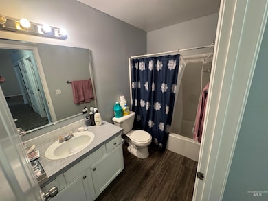 Full bathroom featuring shower / bath combo with shower curtain, dark wood finished floors, and vanity