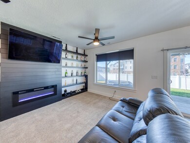Living area featuring a glass covered fireplace, carpet flooring, 2 ceiling fans.