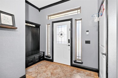 Foyer entrance featuring a textured wall, crown molding, and light tile patterned flooring