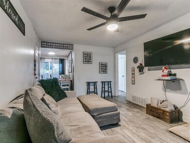 Living room featuring a ceiling fan, a textured ceiling, and wood finished floors