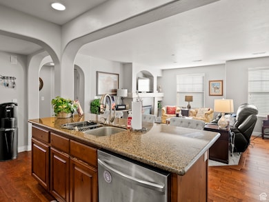 Kitchen featuring dark wood-style floors, an island with sink, dishwasher, and open floor plan