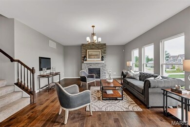 Living area featuring stairs, a chandelier, wood finished floors, and a fireplace