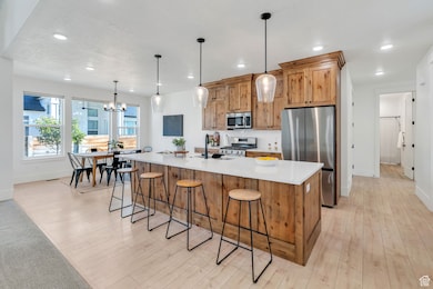Kitchen featuring stainless steel appliances, a kitchen breakfast bar, hanging light fixtures, and recessed lighting