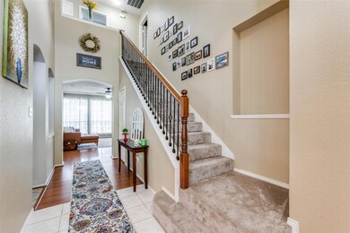 Foyer entrance featuring a high ceiling and view of stairway with rod iron decorative spindles.
