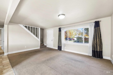 Unfurnished living room with stairway and light colored carpet