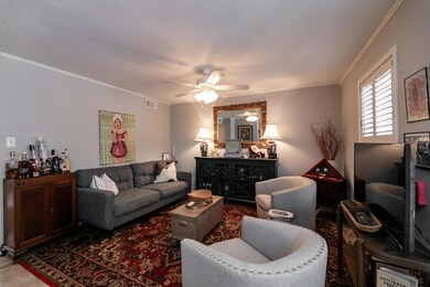 Living room with ceiling fan, a textured ceiling, and ornamental molding