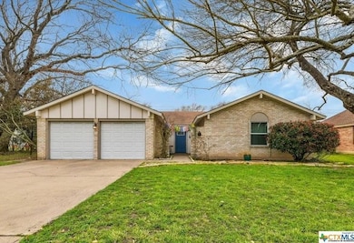 Ranch-style home with driveway, board and batten siding, a front yard, brick siding, and a garage