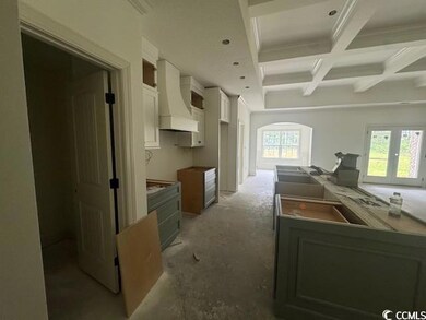 Kitchen with custom exhaust hood, beamed ceiling, white cabinetry, coffered ceiling, and a sink