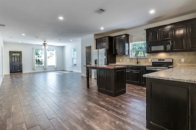 Kitchen featuring tasteful backsplash, open floor plan, a center island, dark wood-style floors, and recessed lighting