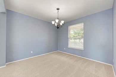 Carpeted empty room with a chandelier and baseboa