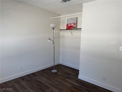 Empty room featuring dark wood-style flooring and a textured ceiling