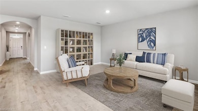 Living room featuring arched walkways, wood finished floors, baseboards, and recessed lighting