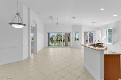 Kitchen with light stone countertops, a center island with sink, light tile patterned floors, lofted ceiling, and pendant lighting