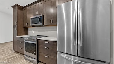 Kitchen featuring dark brown cabinetry, light hard