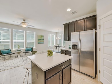 Kitchen featuring stainless steel fridge, dark brown cabinetry, a kitchen breakfast bar, recessed lighting, and a center island