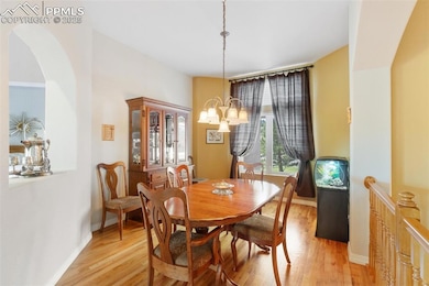 Dining area with light wood-type flooring, arched walkways, and a chandelier