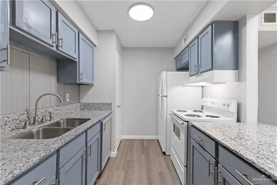 Kitchen with under cabinet range hood, white appliances, visible vents, a sink, and light wood-style floors