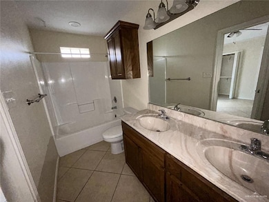 Bathroom featuring tile patterned flooring, toilet, double vanity, and bathing tub / shower combination