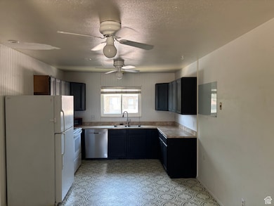 Kitchen with white appliances, light countertops, ceiling fan, and a textured ceiling