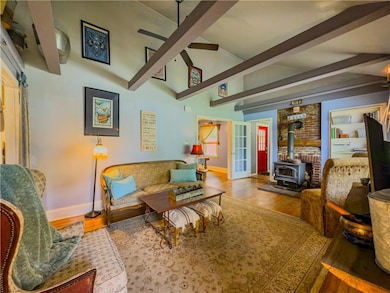 Living area featuring ceiling fan, a wood stove, and wood finished floors