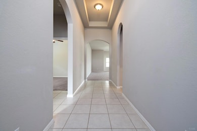Corridor featuring arched walkways, light tile pa