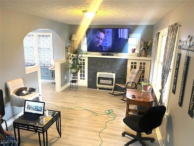 Living area with a textured ceiling, wood finished floors, heating unit, a high end fireplace, and arched walkways