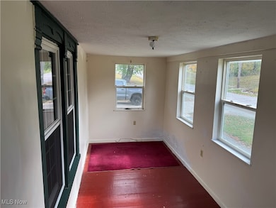 Unfurnished room featuring dark wood-style floors, healthy amount of natural light, and a textured ceiling