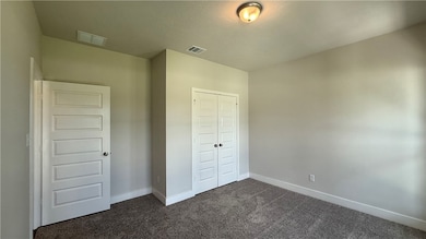 Unfurnished bedroom with dark colored carpet and a
