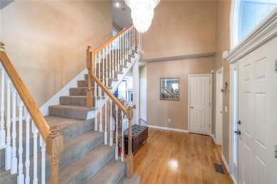Foyer entrance featuring wood finished floors, a towering ceiling, stairway, and a chandelier