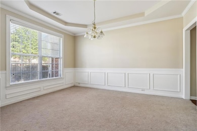 Carpeted spare room featuring a chandelier, a rais